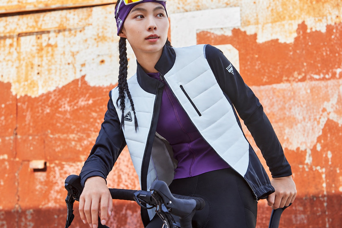 A rider wearing a DEER cycling jacket beside a road bike.