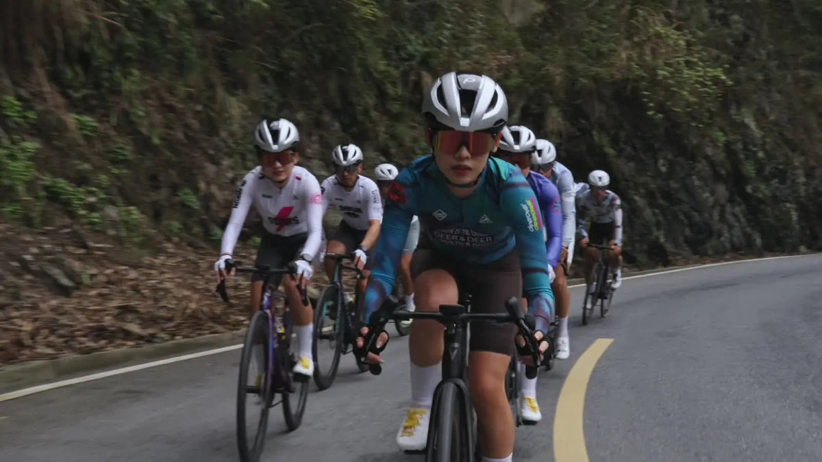 Riders in DEER cycling apparel on a wooded road.