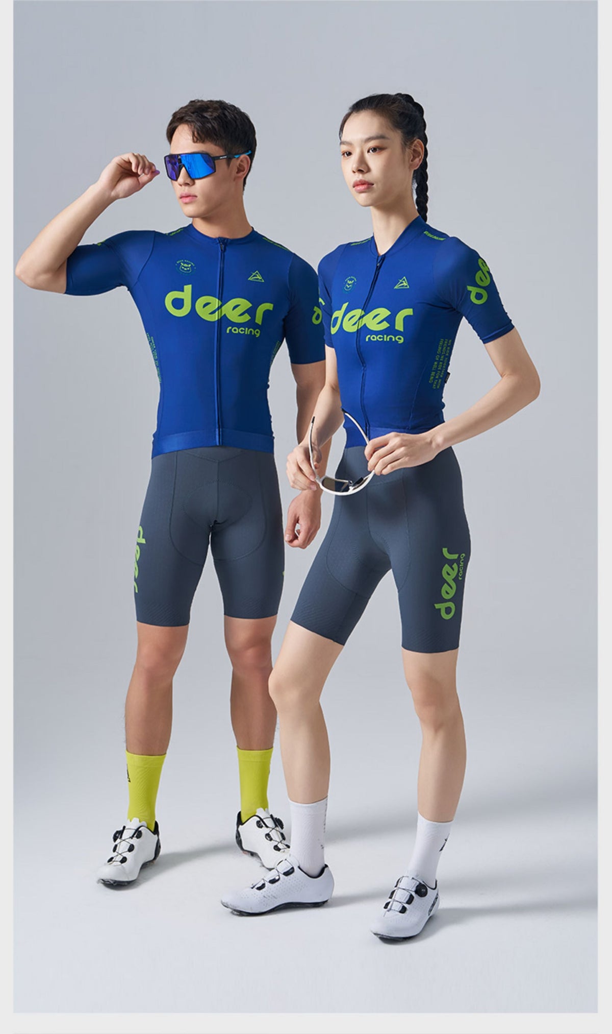 Two riders wearing coordinated blue and lime DEER cycling jerseys and bib shorts.