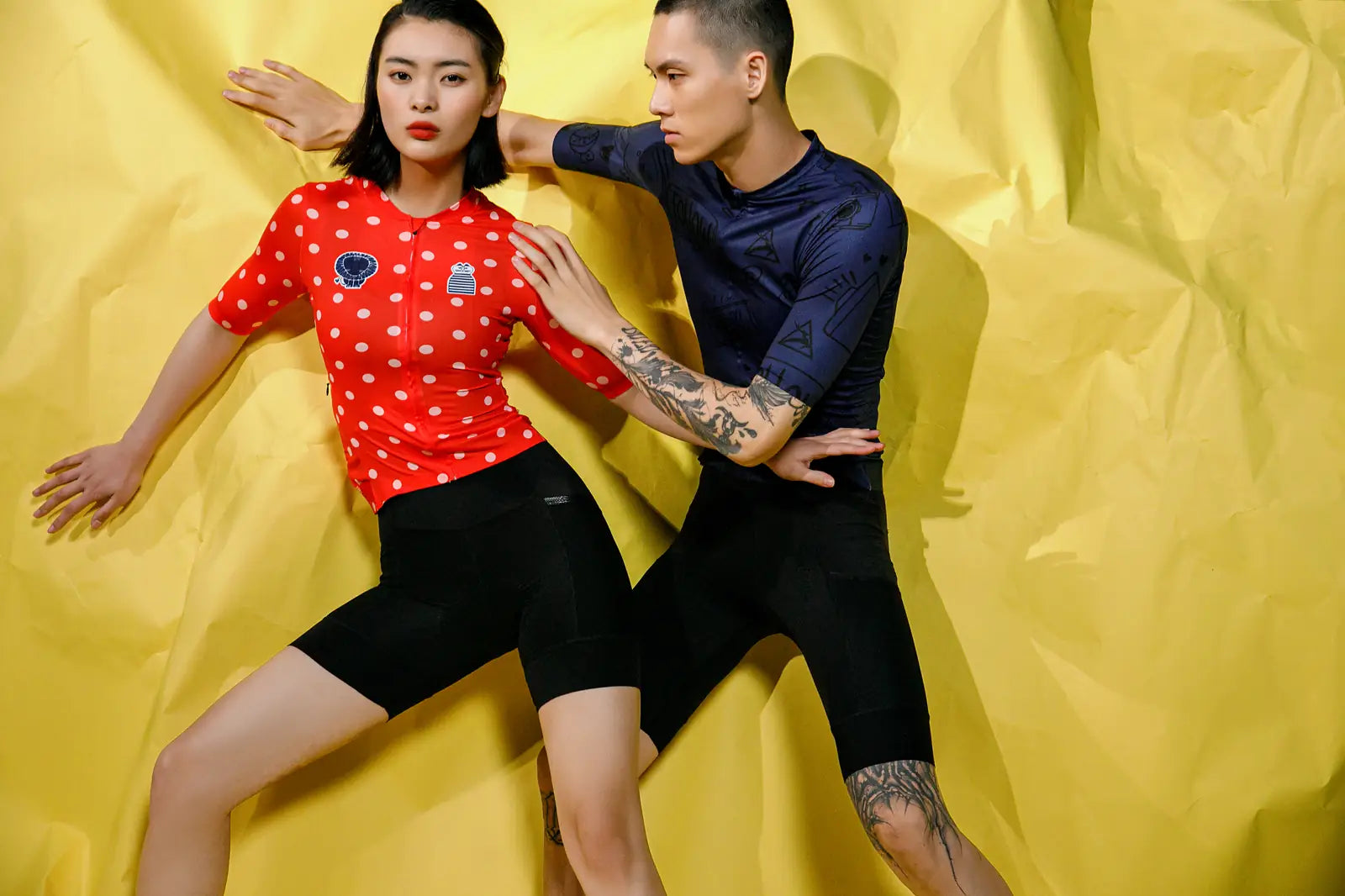 Two people wearing cycling apparel against a yellow background.